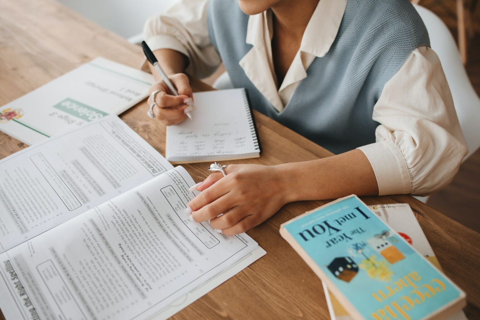 Person working on studying materials on a wooden table.