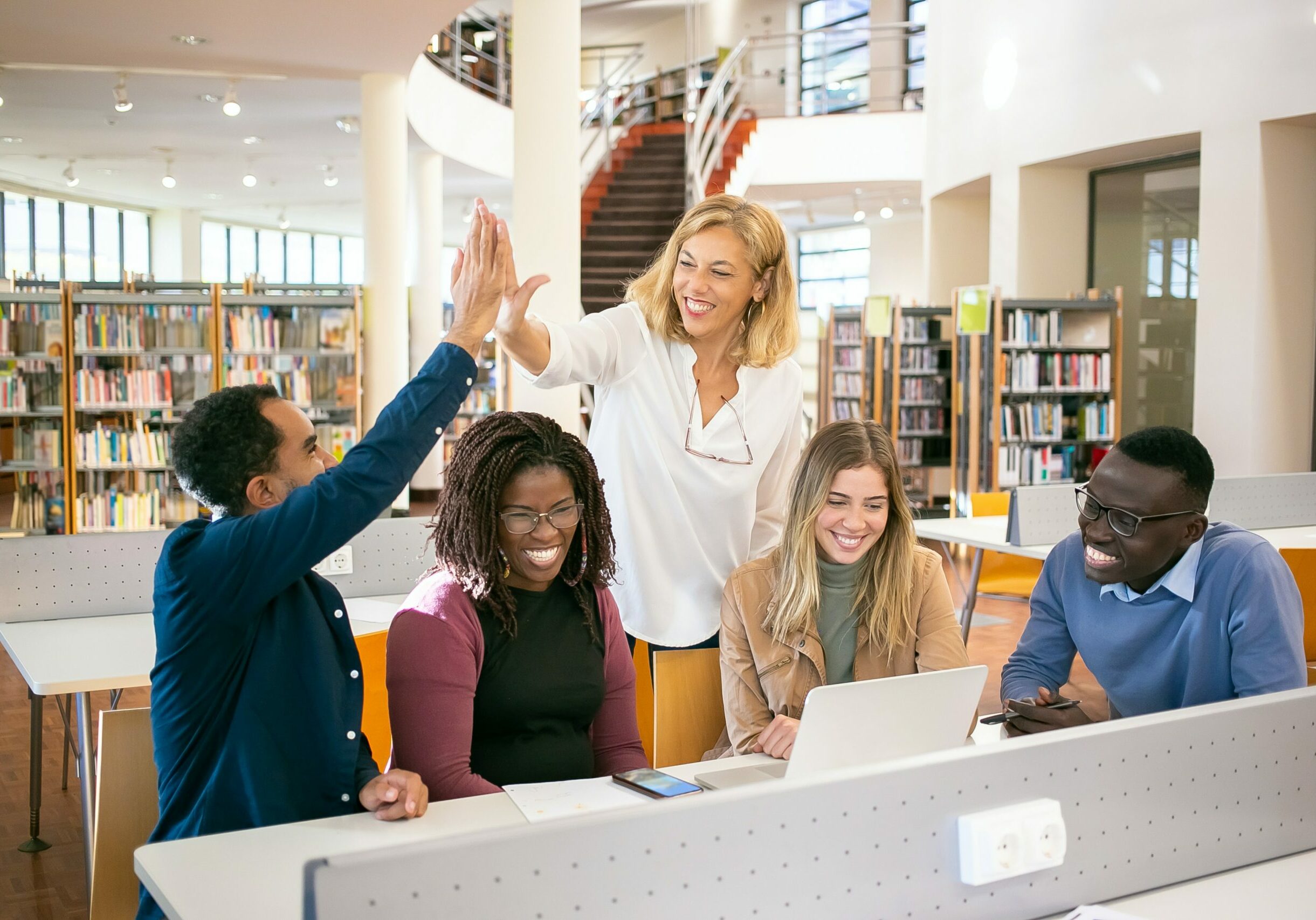 A group of people with a laptop in front of them appear successful when completing a task in the bookstore.