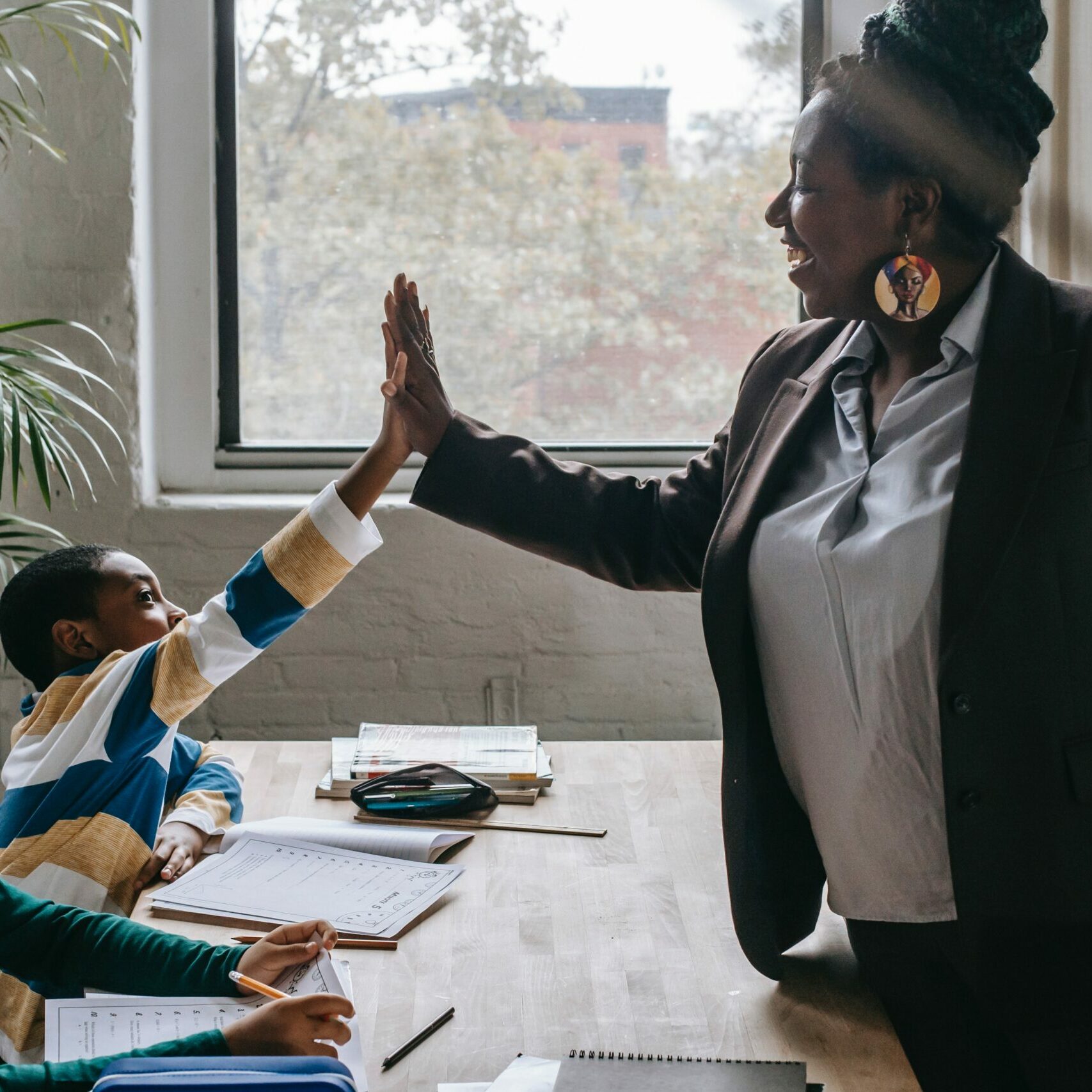 Two students sitting on a bench, one of them high-fiving the teacher.